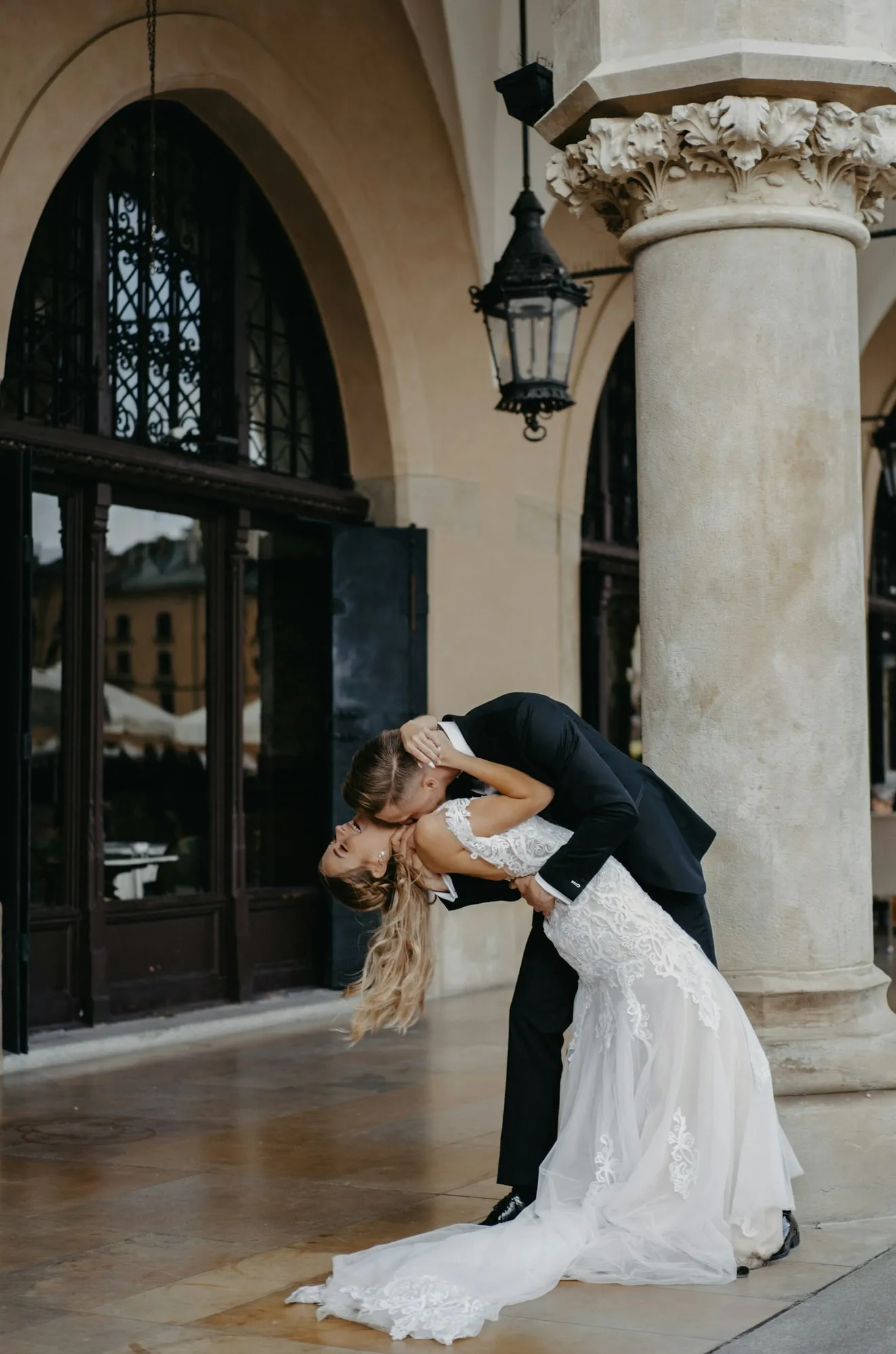 Le marié fait basculer la mariée sous les arcades d’un palais