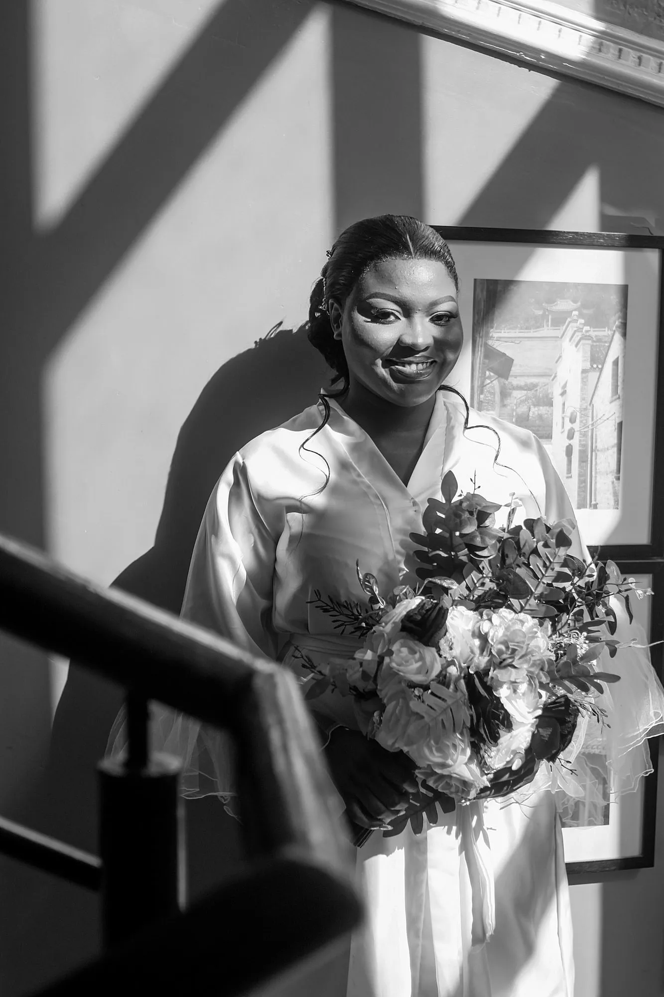 La mariée sourit, bouquet à la main, en noir et blanc