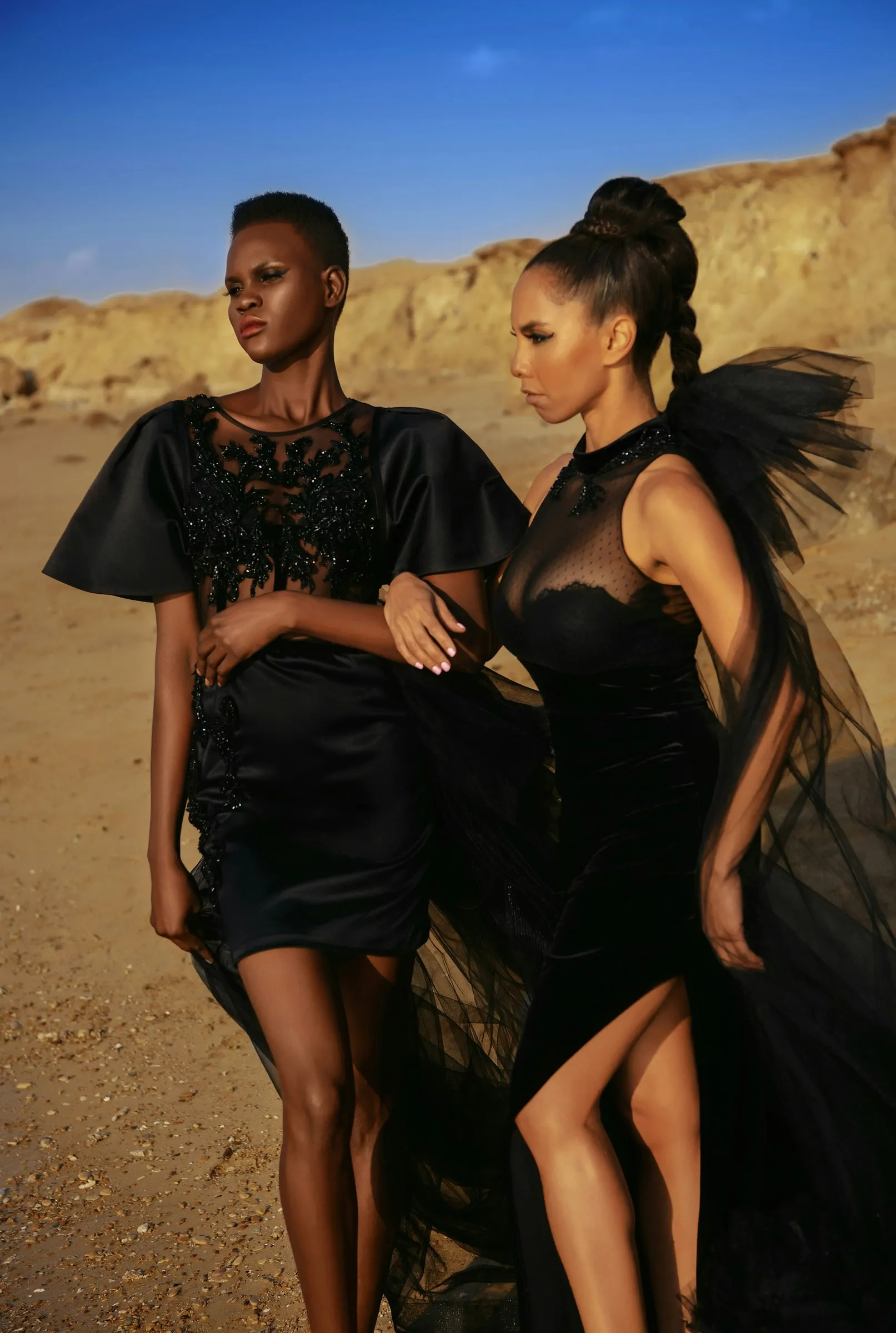 Two women in black gowns in the dunes