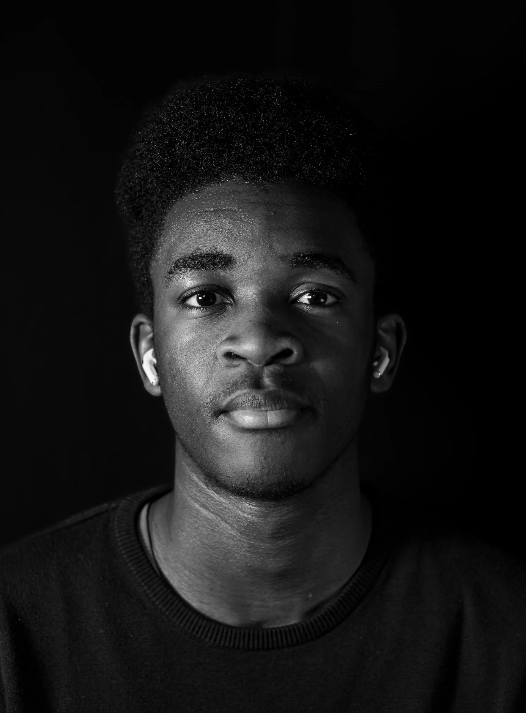 Portrait en noir et blanc d’un jeune homme, lumière unique sur fond noir