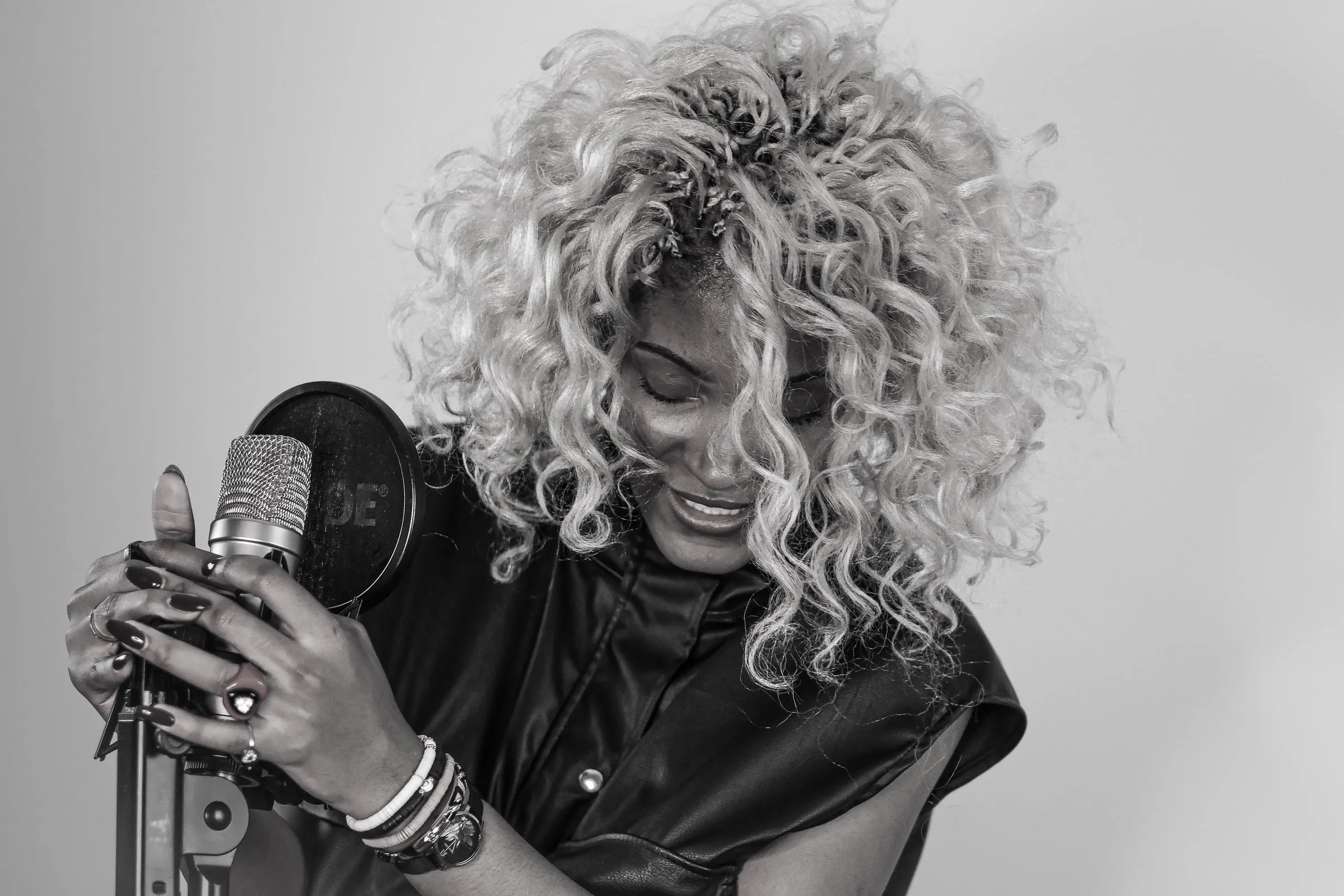 Curly-haired singer holding a microphone, in black and white